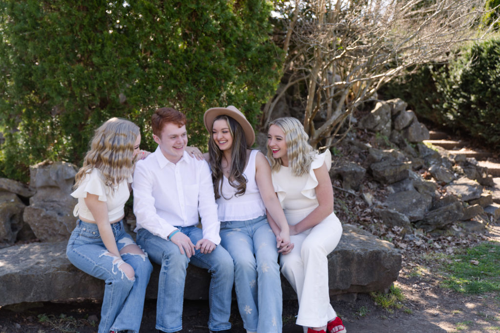 high school senior photographer klem photography captures genuine laughter from 2023 senior model team reps dressed in white shirts with blue denim and red shoes taking senior pictures in nashville tn at centennial park