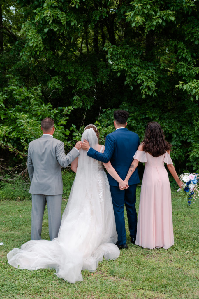 maid of honor holds hands with bride as groom and best man fist bump at a kentucky wedding by klem photography