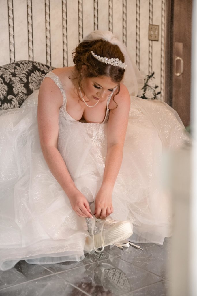 bride tying her converse wedding shoes at a kentucky wedding by klem photography 