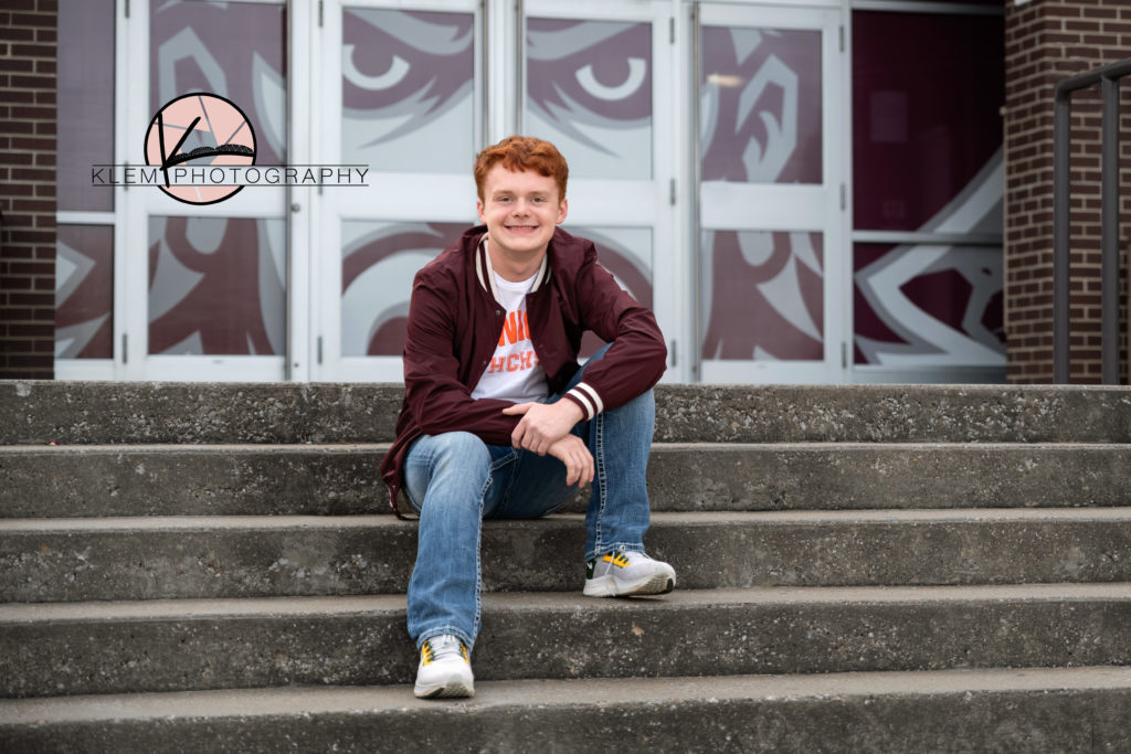guy senior session in kentucky by klem photography kentucky senior photographer. guy is wearing white shirt and maroon track jacket  and jeans. He has wavy red hair