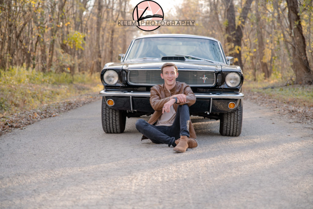 Senior Pictures Evansville IN senior guy sits in front of his classic black mustang