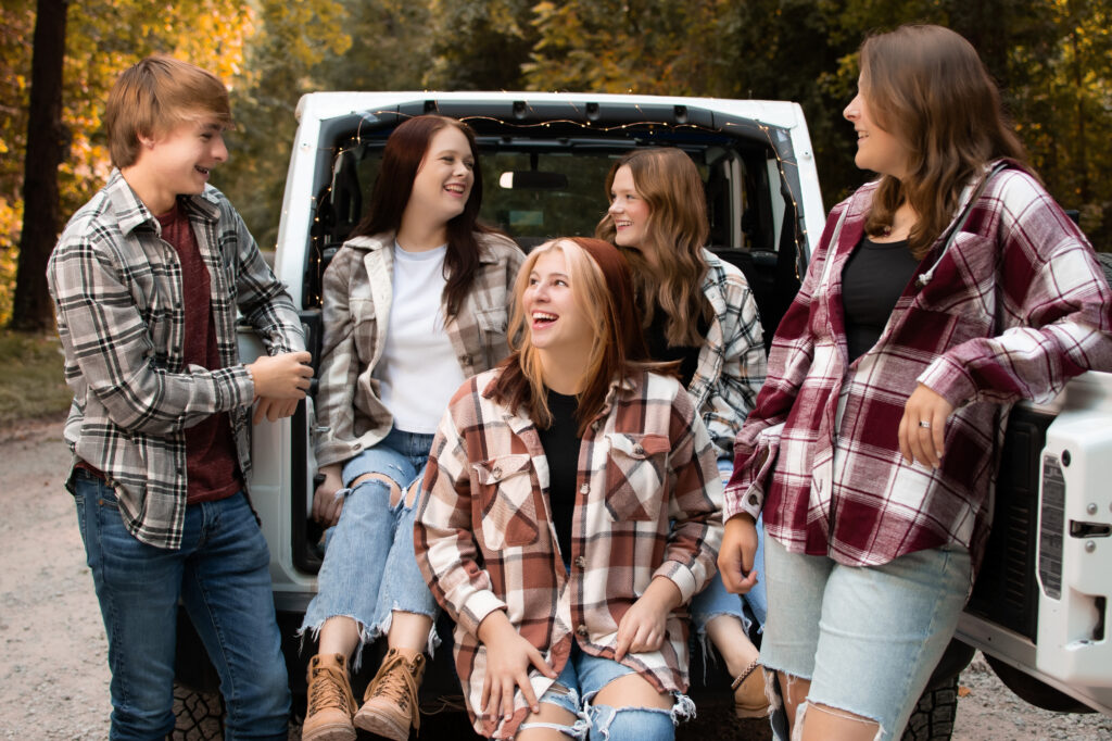 fall senior portraits in henderson ky by klem photography. A group of high school seniors wearing plaid shirts stands around the back of a jeep laughing 