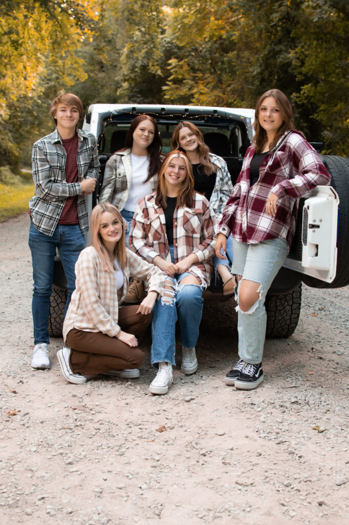 fall senior portraits in henderson ky klem photography kentucky senior photographer klem photography senior model team stands in front of the back of a white jeep smiling at the camera. They all wear fall flannels 
