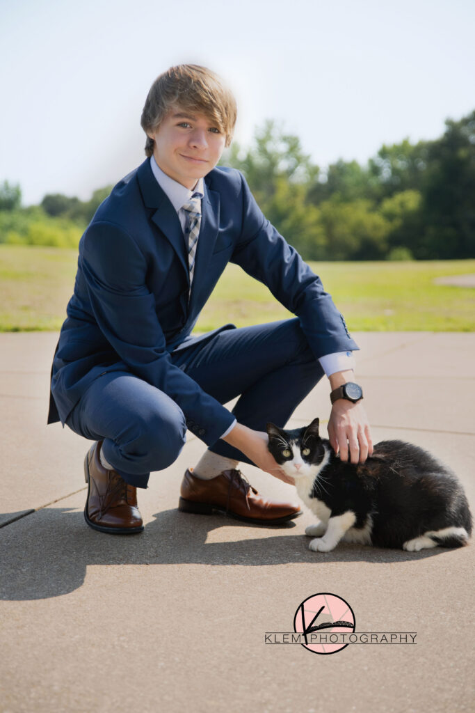 senior photos henderson ky with senior boy squatting down petting his black and white cat