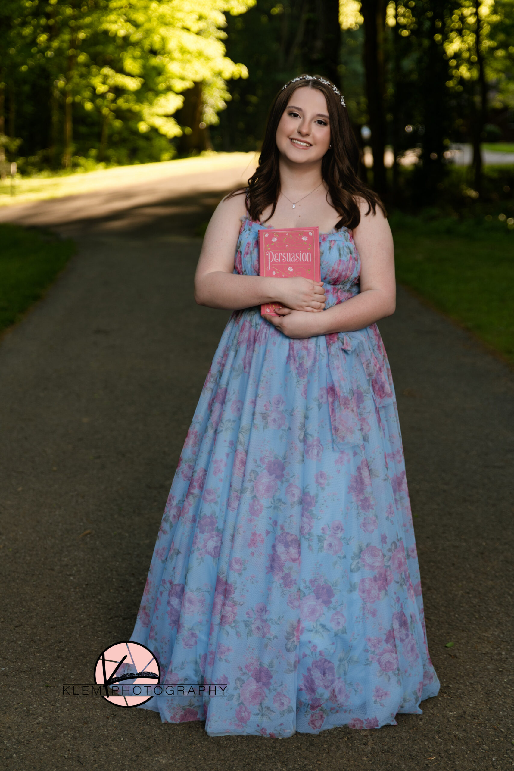 Castle High School Newburgh Indiana senior pictures with Klem photography at Audubon Park in Henderson KY as girl stands in blue prom dress holding Persuasion by Jane Austin.