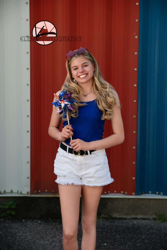 Senior girl holding American flag pinwheel for patriotic senior pictures near Skateway USA in Henderson, Kentucky.

